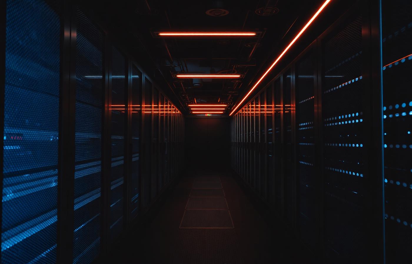Dark data centre corridor lit by amber indicator lighting, representing production infrastructure